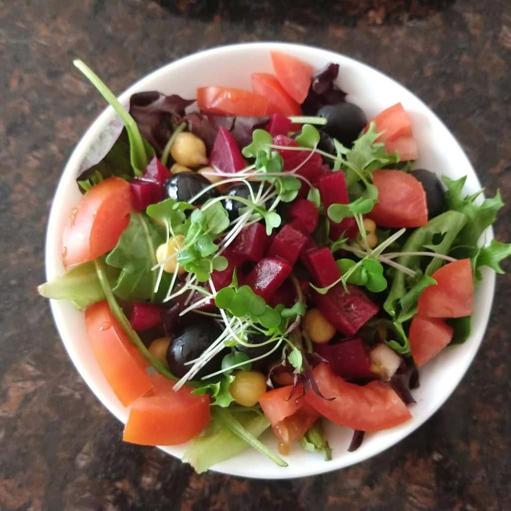 microgreens added into a salad with tomatoes, beats, and olives.