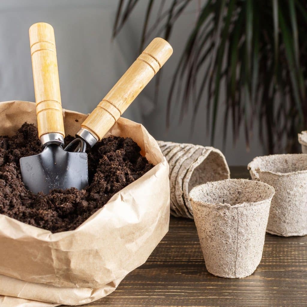 A bag of potting mix with compostable plant containers
