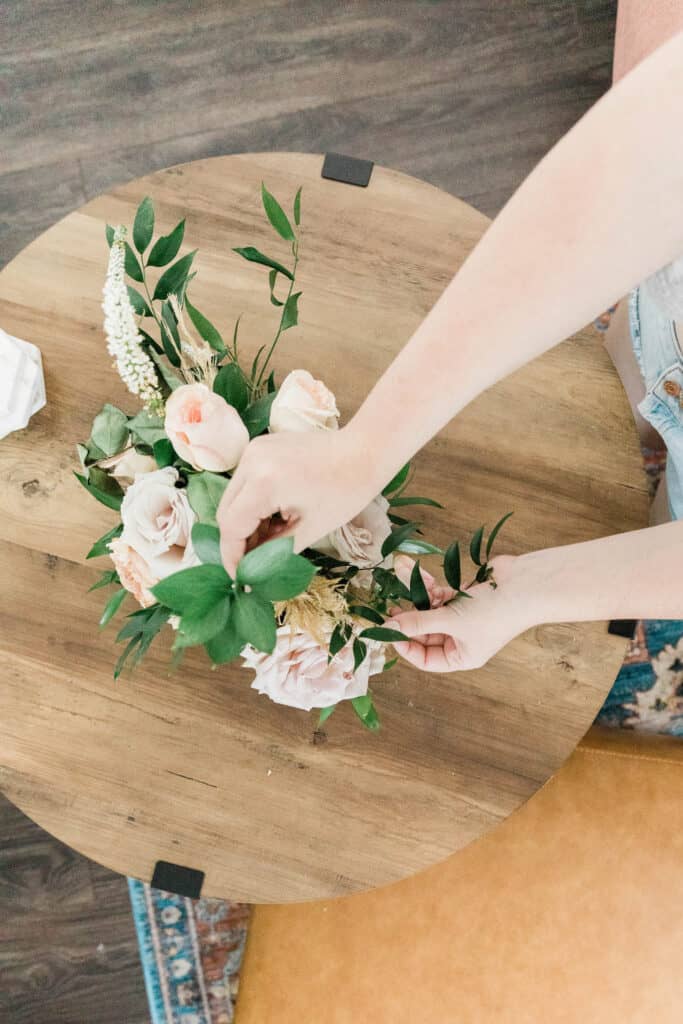 A woman arranging a vase of flowers.