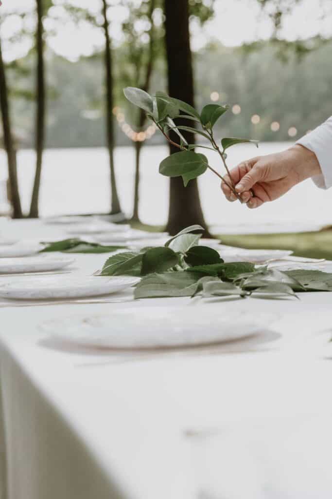 A table setting with flowers and leaves being set on it.