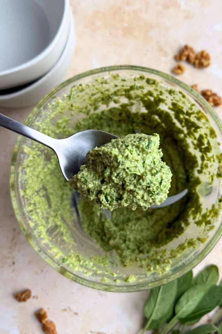 Spoonful of sage pesto over a food processor.